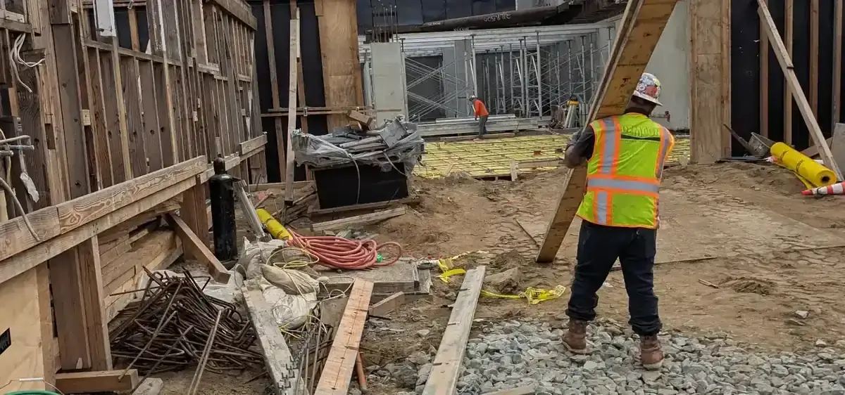 Construction site laborer hauling demolition debris in wheelbarrow on San Diego job site