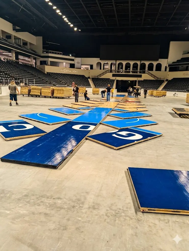 Logistics crew installing interlocking hardwood basketball court over arena concrete floor
