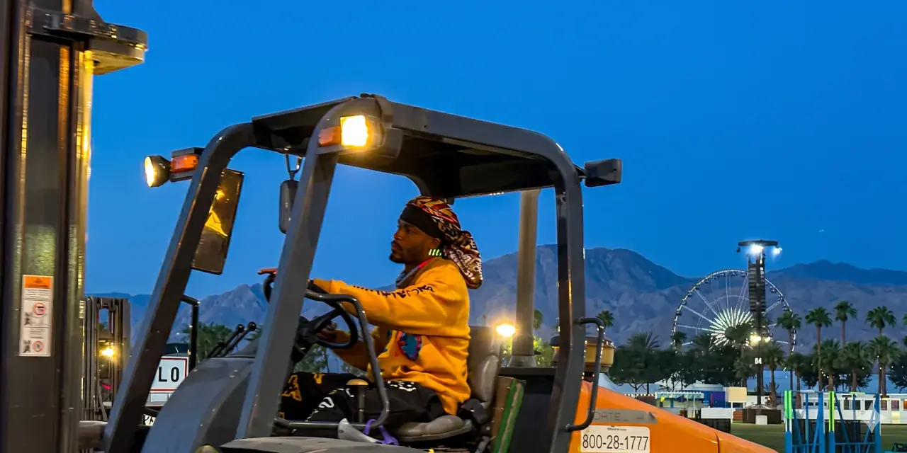 Forklift operator and gear handler moving equipment in a production warehouse